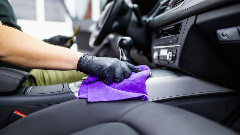 Gloved hand cleaning a car's interior